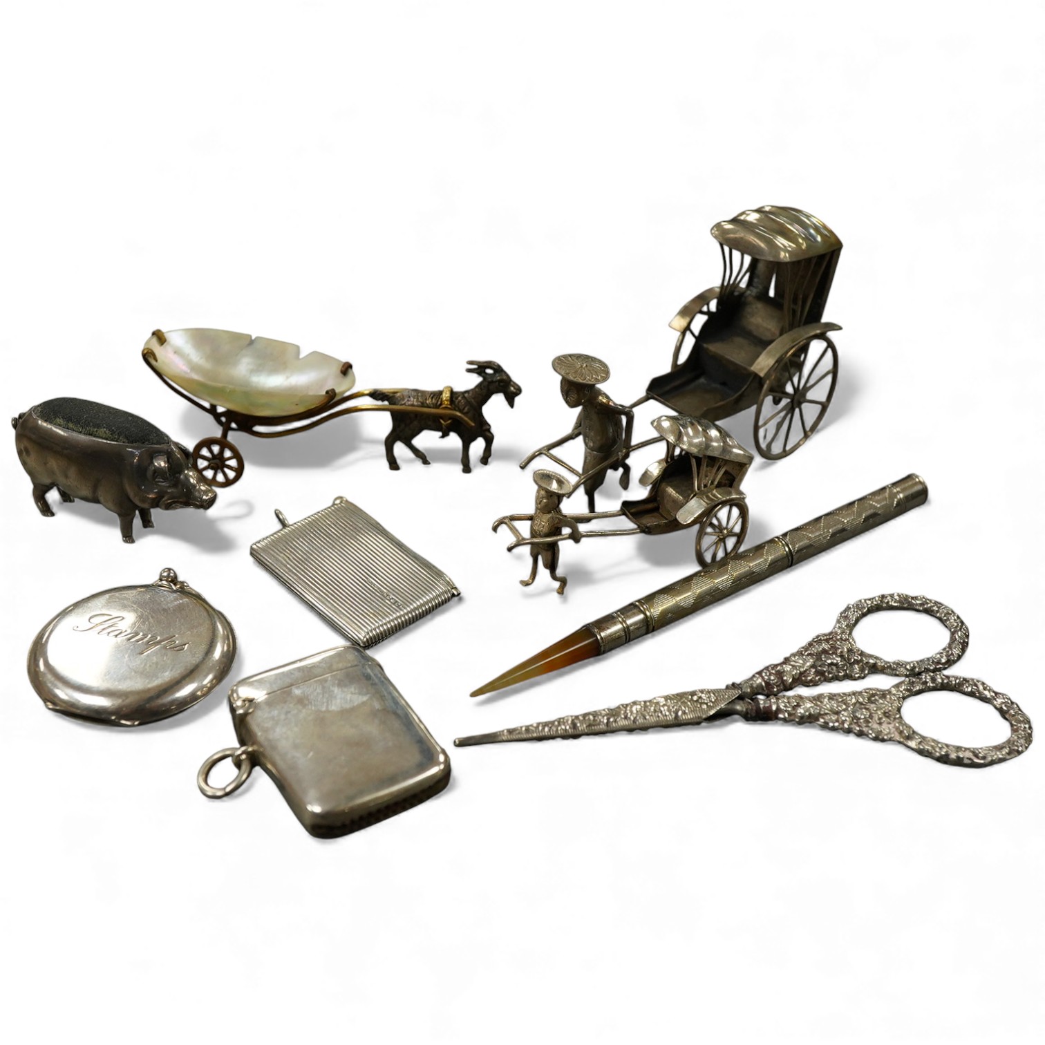 Sundry small silver and other items including a pig pin cushion, Adie & Lovekin, Birmingham, 1906, 45mm, a silver circular stamp case, a silver vesta case, a small sterling mounted notecase, three small metal rickshaws,